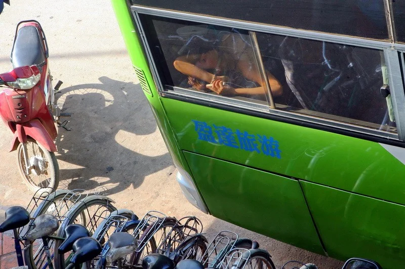 Cambodia./ Девушка спит в туристическом автобусе на городской улице Сиемриепа в Камбодже